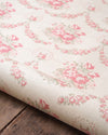 Roll of floral wallpaper with pink flowers on a wooden surface