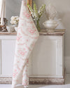 Floral-patterned towel draped over a decorative cabinet with floral arrangements.