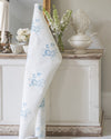 White towel with blue floral pattern draped over a wooden cabinet in a room with decorative items.