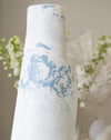 Roll of oilcloth with blue floral design against a neutral background
