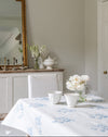 Dining room with a table set for a meal, featuring a floral tablecloth and white tableware.