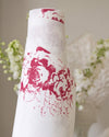 White vase with red floral patterns against a blurred floral background