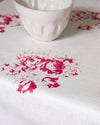 White ceramic cup on a white surface with pink floral patterns