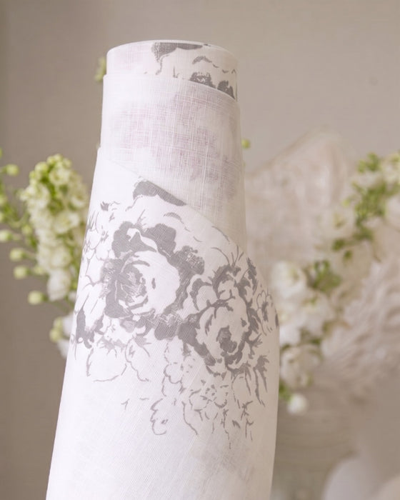 White vase with black floral patterns against a blurred floral background