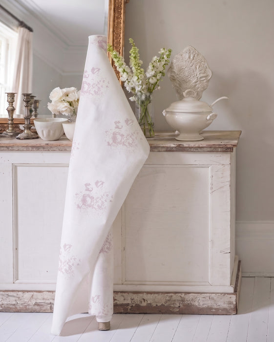 Floral-patterned fabric draped over a decorative object in a room with a mirror and flowers.