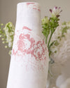 White vase with pink floral pattern against a blurred floral background