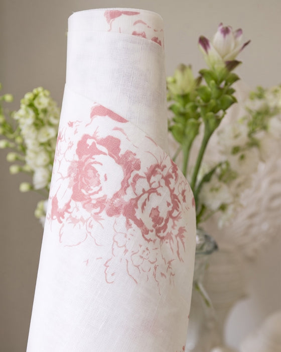 White vase with pink floral pattern against a blurred floral background