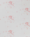A close-up image of white linen fabric with a repeated floral pattern in a pink hue.